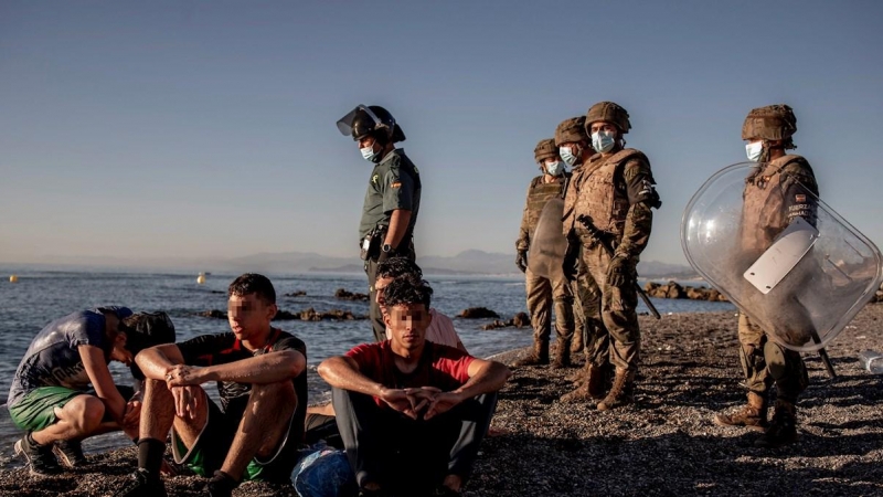 Miembros del ejército observan a un grupo de inmigrantes menores a su llegada a la playa de El Tarajal en Ceuta.