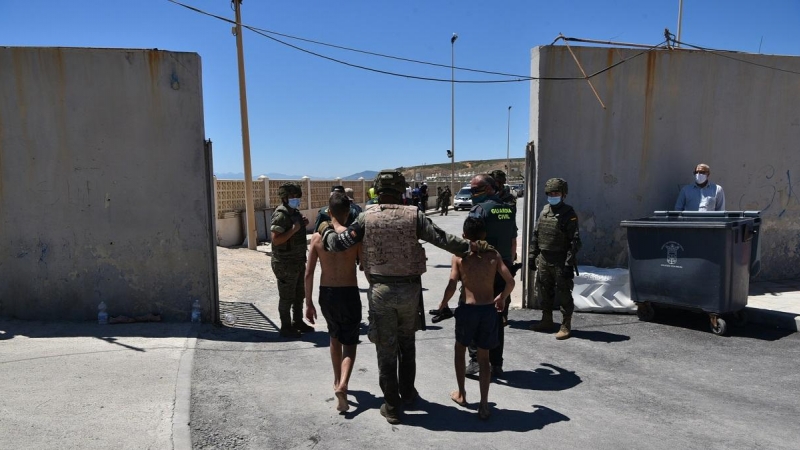 Un militar del ejército español y un agente de la Guardia Civil ayudan a dos menores migrantes procedentes de Marruecos a su llegada a Ceuta, a 19 de mayo