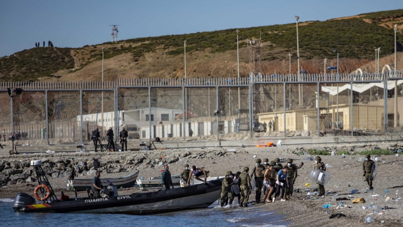 Las fuerzas armadas dirigen a un grupo de jóvenes que han cruzado a nado la frontera de Marruecos hasta llegar a la playa de Tarajal en Ceuta.