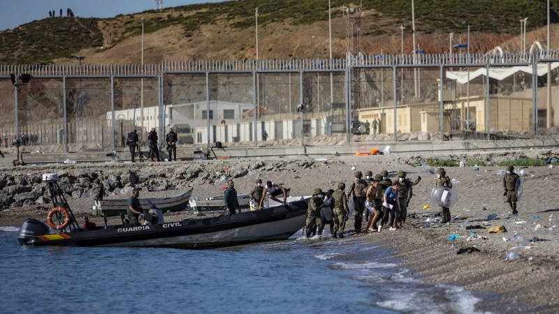 Las fuerzas armadas dirigen a un grupo de jóvenes que han cruzado a nado la frontera de Marruecos hasta llegar a la playa de Tarajal en Ceuta.