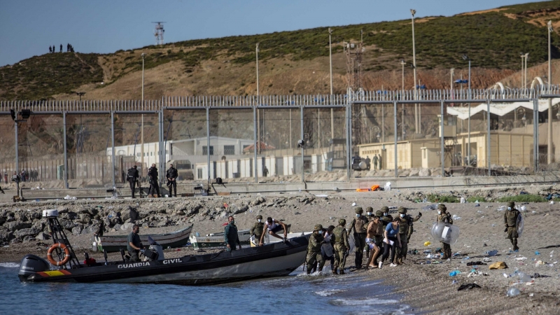 Las fuerzas armadas dirigen a un grupo de jóvenes que han cruzado a nado la frontera de Marruecos hasta llegar a la playa de Tarajal en Ceuta.