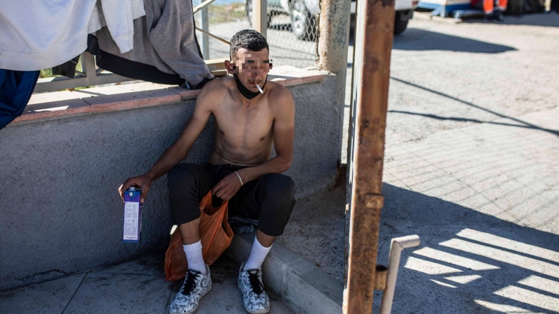 Un joven descansa fumándose un cigarrillo tras haber cruzado a nado la frontera de Ceuta con Marruecos.