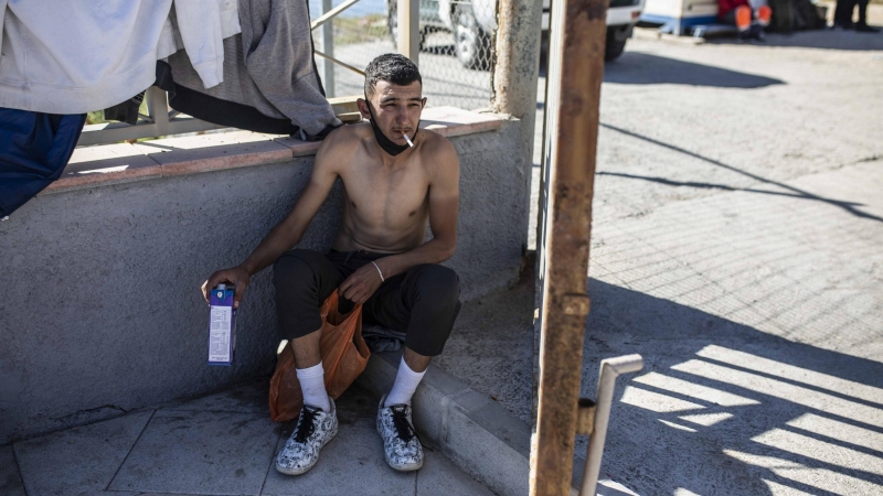 Un hombre se fuma un cigarrillo mientras descansa tras cruzar a nado la frontera hasta Ceuta.