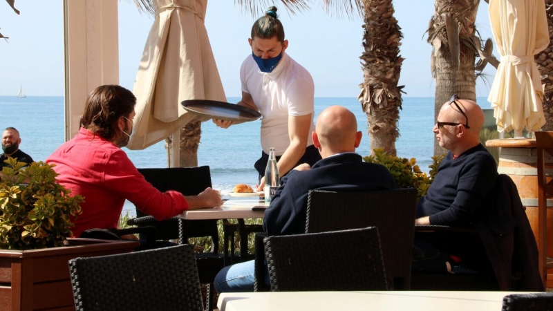 Un cambrer servint una taula en una terrassa de Sitges. Imatge del diumenge 28 de març del 2021.