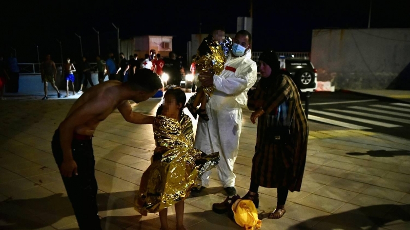 Un hombre migrante coge en brazos a un menor acompañado de una mujer y una niña pequeña, a 17 de mayo de 2021, en Ceuta (España).