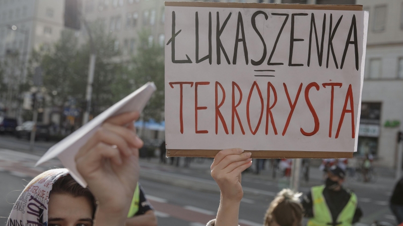 Una persona muestra un letrero en el que llama 'terrorista' al presidente bielorruso, en Varsovia (Polonia). - Reuters