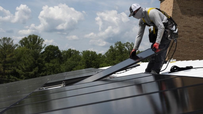 Un operario coloca una placa solar en el tejado de un edificio de EEUU.