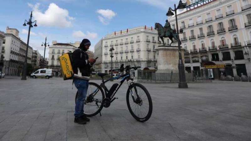 Un repartidor de la empresa Glovo mira su teléfono en la Puerta del Sol. — Marta Fernández / EUROPA PRESS
