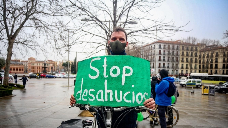 Un hombre con un cartel en el que se lee: `Stop desahucios´ en el final de la bicicletada durante una manifestación por el derecho a la Vivienda en Atocha, Madrid (España), a 21 de febrero de 2021.