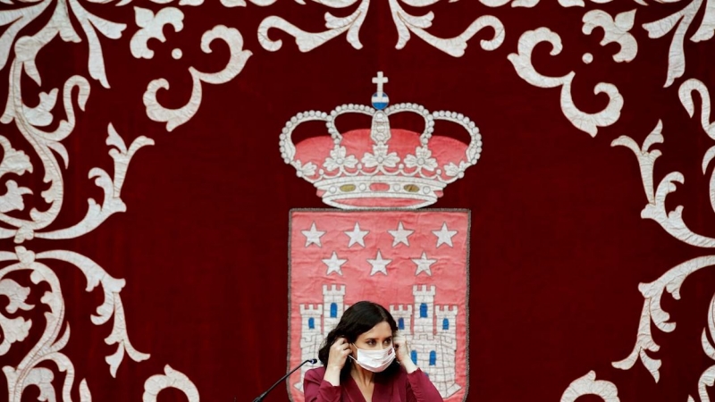 La presidenta madrileña, Isabel Díaz Ayuso, se coloca la mascarilla mientras preside la ceremonia de toma de posesión de los nuevos consejeros de la Comunidad de Madrid, este lunes, en la Real Casa de Correos.