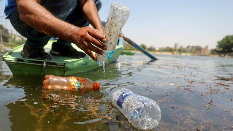 Un pescador recoge dos botellas de plástico arrojadas al río Nilo, Egipto.