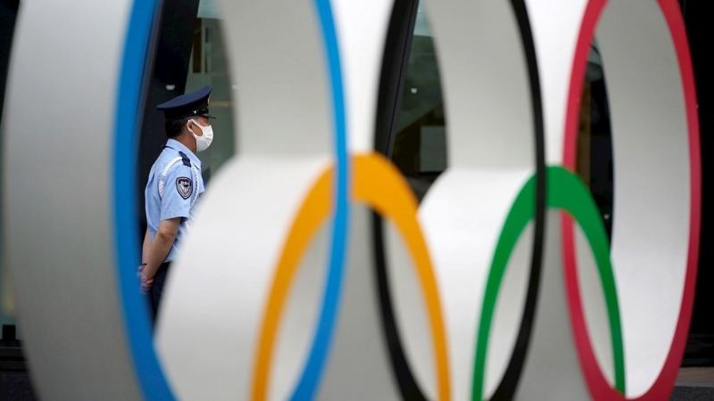 Un guardia de seguridad detrás del monumento de los anillos olímpicos en las inmediaciones del estadio olímpico de Tokio.