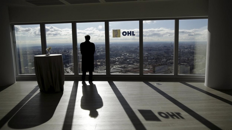 Un hombre mira a través de un ventanal de la sede en Madrid de la constructora OHL. REUTERS/Andrea Comas