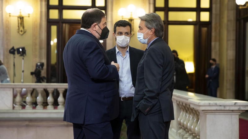 L'expresident Artur Mas i l'exvicepresident Oriol Junqueras, acompanyat d'un col·laborador, xerren abans de la investidura del president de la Generalitat, Pere Aragonès, el 21 de maig de 2021.