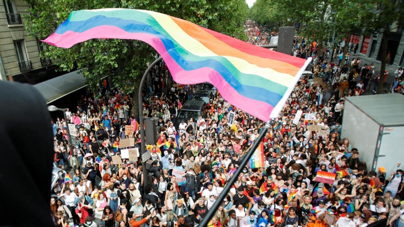 Una persona ondea una bandera del arco iris sobre una multitud de participantes de la tradicional marcha del Orgullo LGBTQ, en medio del brote de la enfermedad del coronavirus (COVID-19), en París, Francia, el 26 de junio de 2021.