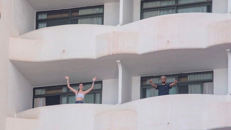 Dos jóvenes que permanecen en aislamiento en el hotel Palma Bellver de Palma saludan desde los balcones de sus habitaciones, este martes 29 de junio en Palma de Mallorca.