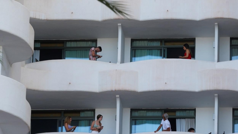 Varios de los jóvenes que permanecen en aislamiento en el hotel Palma Bellver de Palma, en los balcones de sus habitaciones.  REUTERS/Enrique Calvo