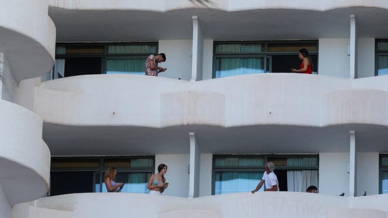 Varios de los jóvenes que permanecen en aislamiento en el hotel Palma Bellver de Palma, en los balcones de sus habitaciones.  REUTERS/Enrique Calvo