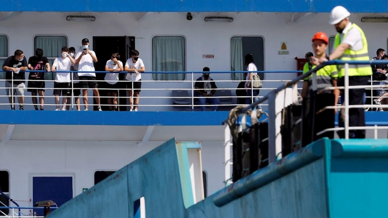 Varias personas aguardan durante el atraque del ferry en el que viajan 118 estudiantes que habían sido confinados en un hotel de Mallorca.