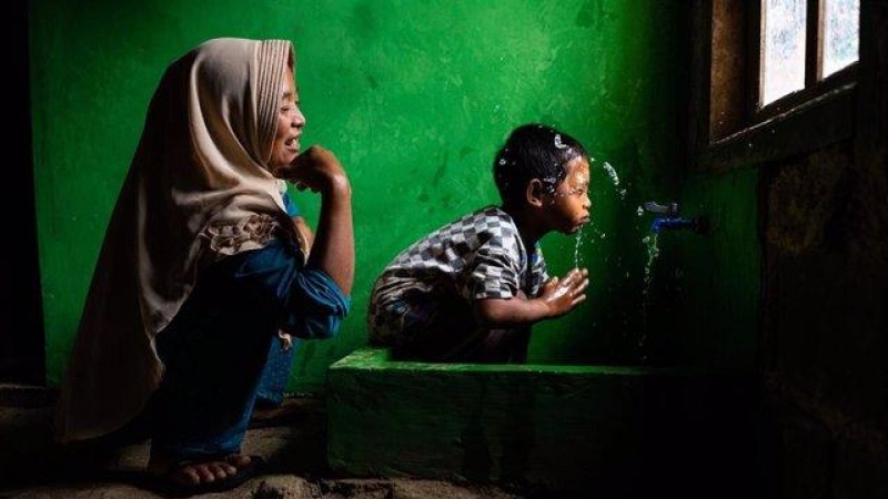 Wahyu observa a su hijo Rizki, de 4 años, lavándose la cara en una nueva instalación de agua potable en su casa, en Tlogopakis, Indonesia.