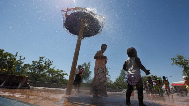 Unos niños juegan en una fuente de agua durante la ola de calor en Canadá.