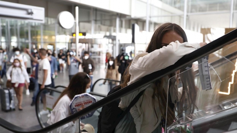 Jóvenes evitan a la prensa tras realizar un cribado por parte de la Xunta, en el aeropuerto de Lavacolla, a su llegada a Santiago procedentes de Mallorca.