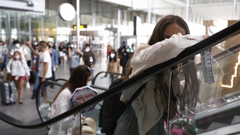 Jóvenes evitan a la prensa tras realizar un cribado por parte de la Xunta, en el aeropuerto de Lavacolla, a su llegada a Santiago procedentes de Mallorca.