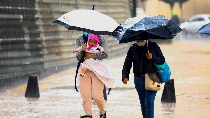 Personas se resguardan de la lluvia este miércoles.