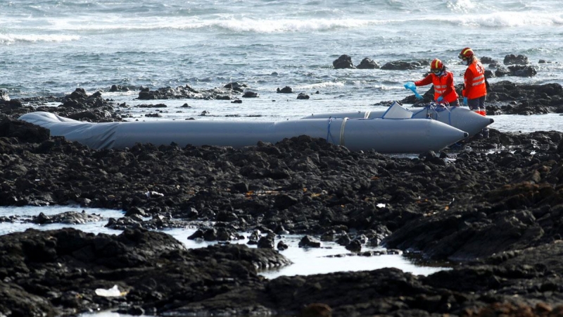 Dos trabajadores de los equipos de rescate, junto a una embarcación neumática en cuyo naufragio murieron cuatro personas y 41 fueron rescatadas el pasado junio en Órzola, Lanzarote.