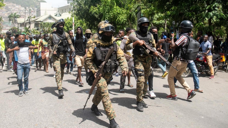 Policías haitianos escoltan a un grupo de personas mientras conducen detenidos a dos extranjeros en Puerto Principe , Haití