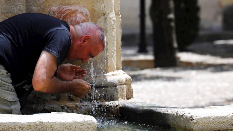Un hombre se refresca en una fuente de Córdoba para intentar sofocar el calor. - EFE