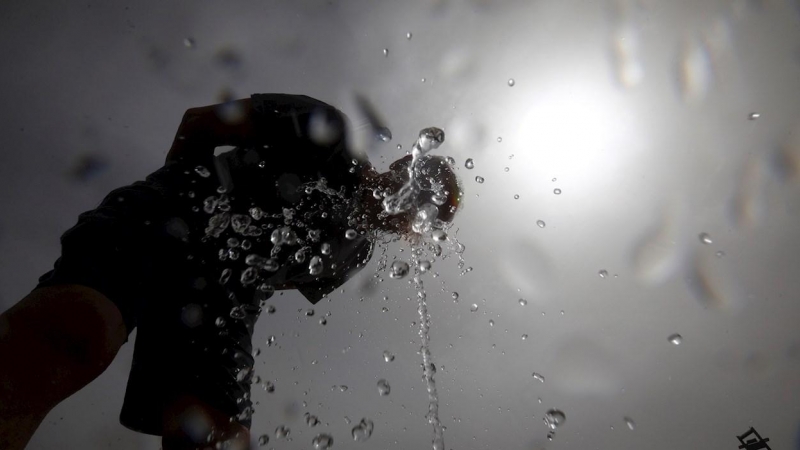 Un hombre se refresca en una de las fuentes de la ciudad para aliviar las altas temperaturas.