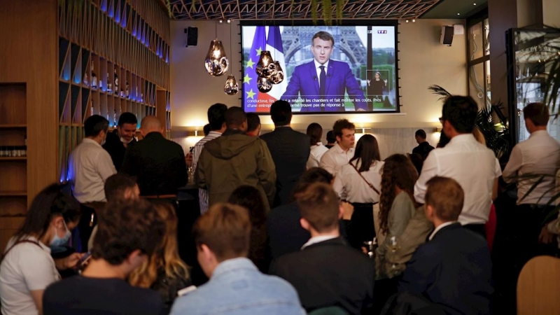 Clientes de un bar en París escuchan al presidente francés, Emmanuel Macron, durante su intervención ante la televisión.