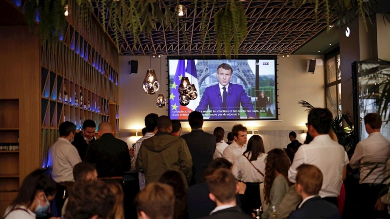 Clientes de un bar en París escuchan al presidente francés, Emmanuel Macron, durante su intervención ante la televisión.