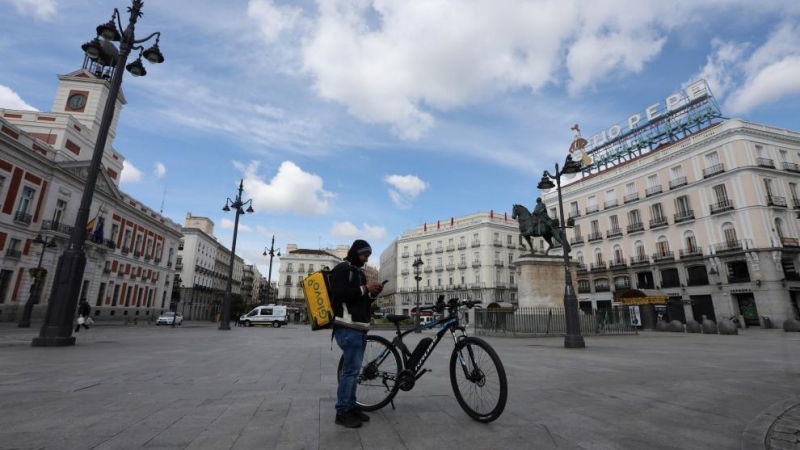 Un repartidor de la empresa Glovo mira su teléfono en la Puerta del Sol. — Marta Fernández / EUROPA PRESS