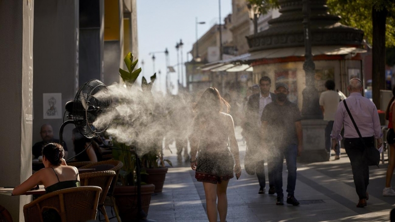 Varias personas caminan al lado de un difusor de vapor de agua de un restaurante en Madrid, en una imagen del 2 de julio de 2021.