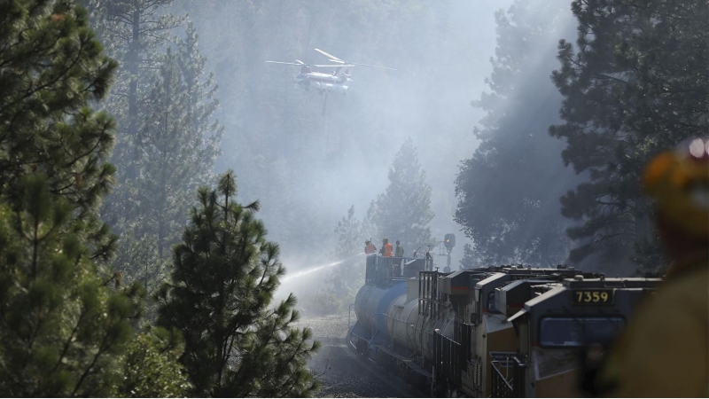 Los bomberos trabajan en las labores de extinción subidos a un tanque de agua para extinguir las llamas.