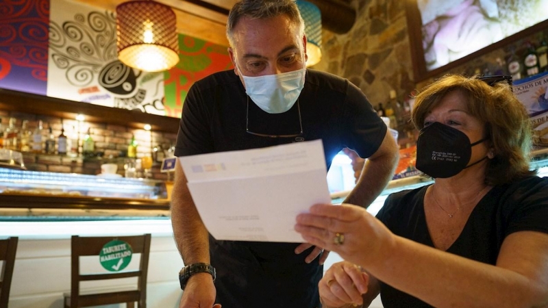 Personal de una cafetería de Santa Cruz de Tenerife, comprueba el certificado Covid de una clienta.