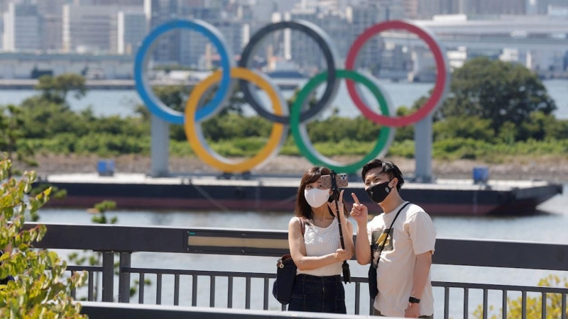 Una pareja se toma fotos frente a los anillos olímpicos en Tokio. EFE/Kai Föersterling