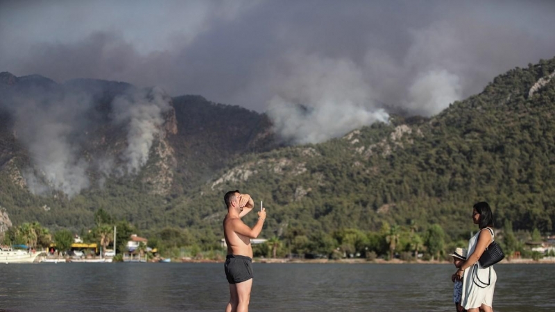 Turistas se hacen fotos con un incendio de fondo