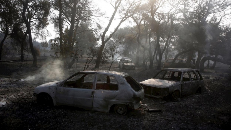 Dos coches quemados tras el incendio que asola el suburbio de Varybobi.