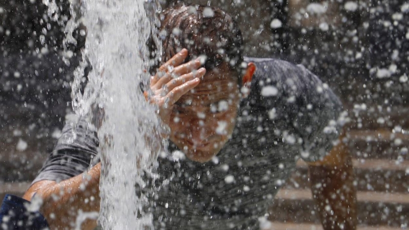 Un hombre se refresca en una fuente de Córdoba.