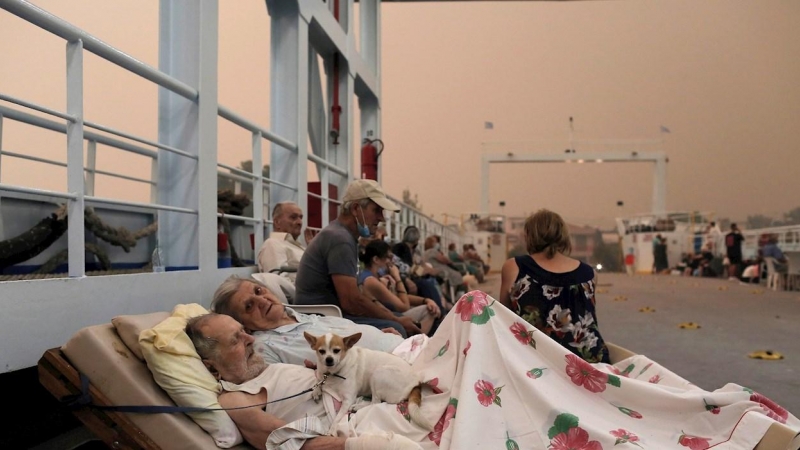 Georgios Liakos 89, y su esposa Parisso Liakou 87, esperan junto con su perro Bella, a bordo de un ferry para ser evacuados al continente durante un incendio forestal en el pueblo de Pefki en la isla de Evia, Grecia, 08 de agosto de 2021