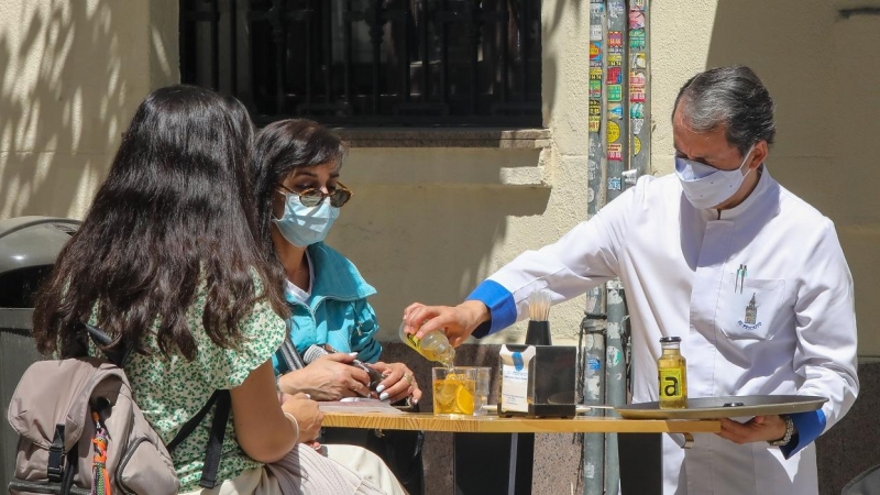 Un camarero sirve un refresco a dos personas en una terraza, en Madrid. e.p./Marta Fernández Jara