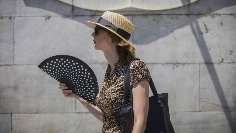 Una mujer se abanica mientras camina por la Avenida de la Constitución, en Sevilla.