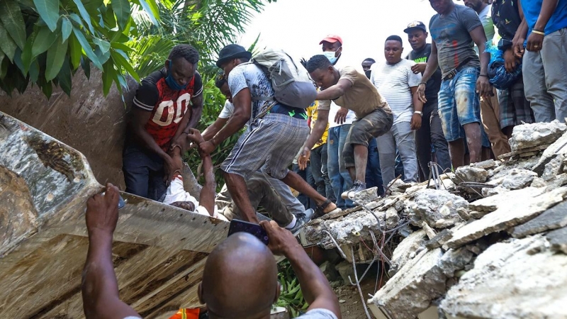 Un grupo de personas sacan un cuerpo de los escombros de un edificio tras el terremoto que ha sacudido de nuevo Haití.