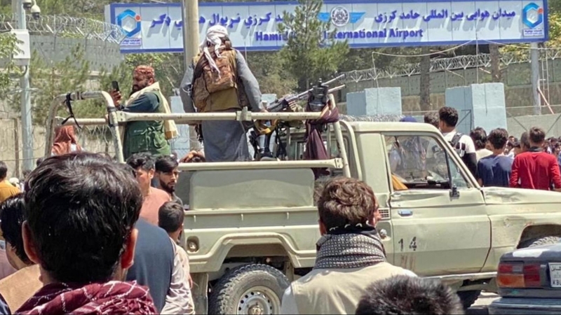 Los talibanes montan guardia frente al aeropuerto internacional Jamid Karzai mientras la gente camina hacia el aeropuerto para huir del país.