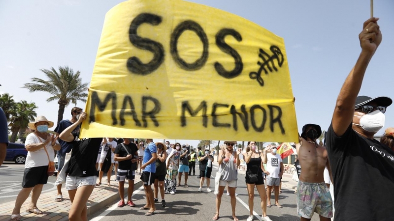 Varias personas participan en una protesta en defensa del Mar Menor al paso de la Vuelta Ciclista a España, a 21 de agosto de 2021, en La Manga.