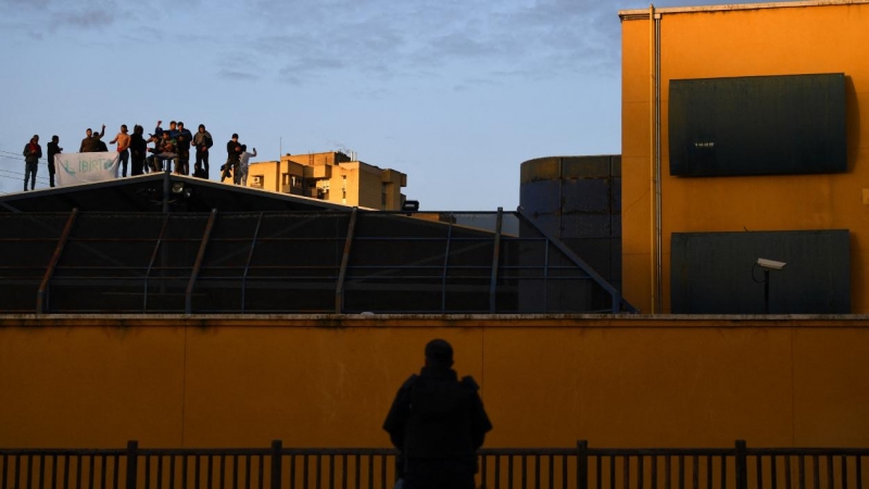 Un policía observa a un grupo de migrantes internados en el CIE de aluche pidiendo su libertad, tras ser declarado el primer confinamiento por la pandemia de covid-19, el 17 de marzo de 2020, Madrid, España.