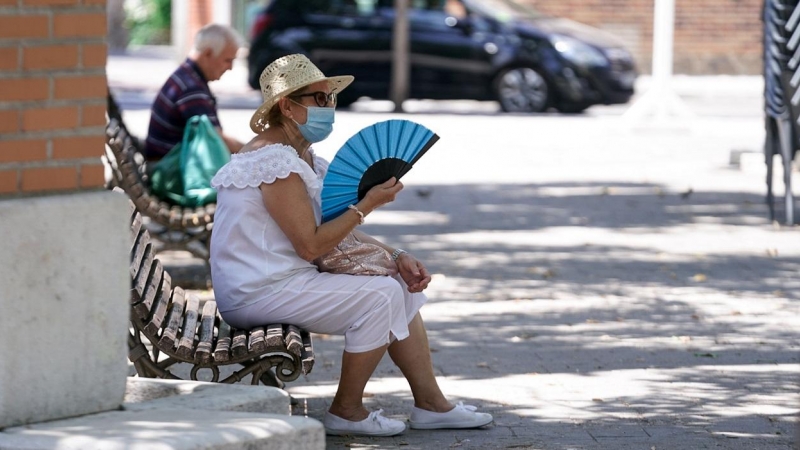 Una anciana con mascarilla se abanica sentada en un banco en Madrid. E.P./A. Pérez Meca